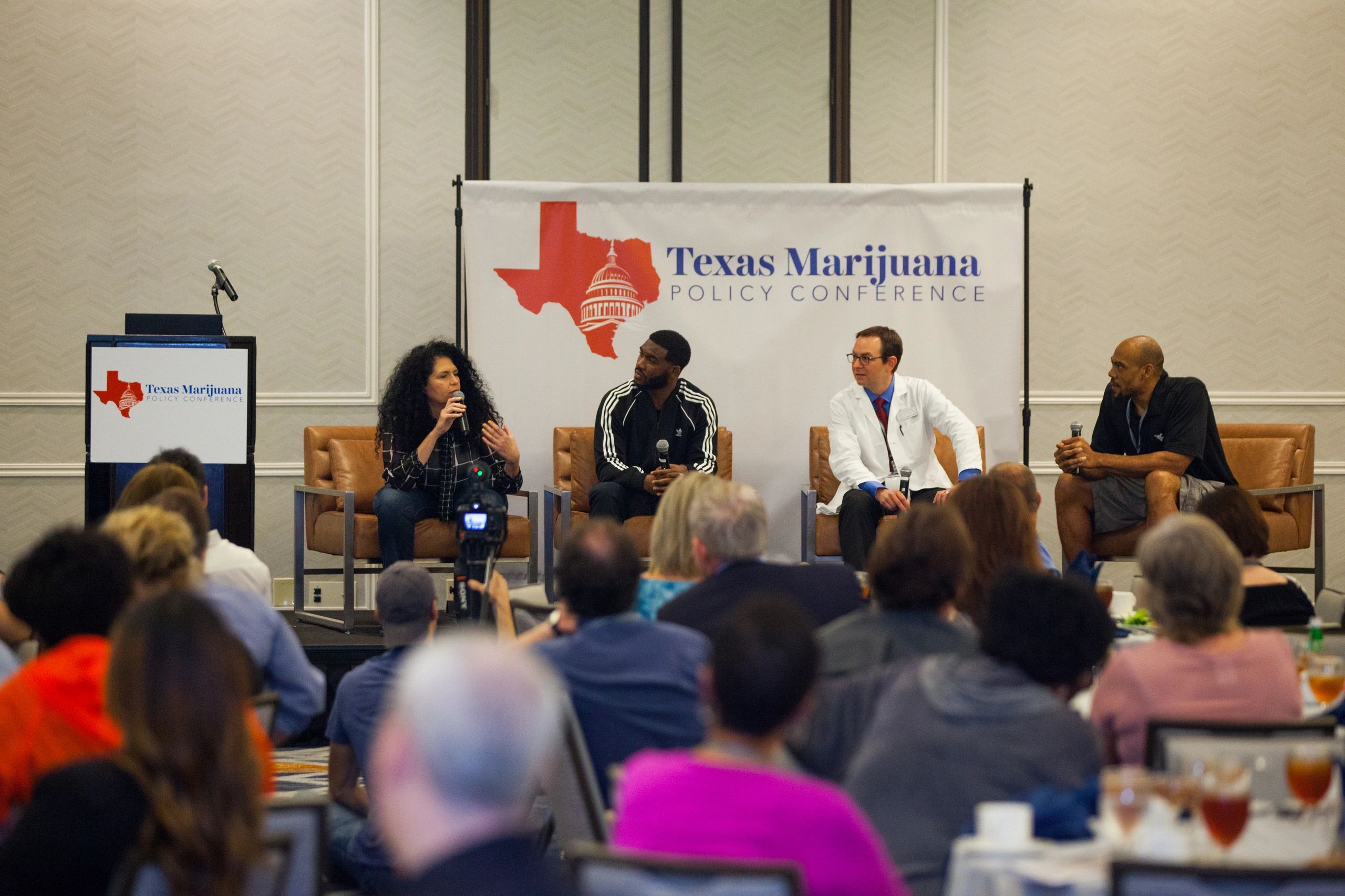 Four panelists on stage in front of an audience at the Texas Marijuana Policy Conference