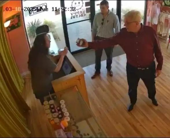 Security camera still from an Austin CBD store showing a man holding out his ID to an employee at the counter